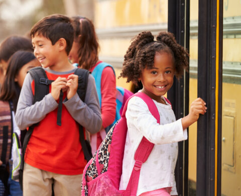 Elementary school girl at the front of the school bus queue