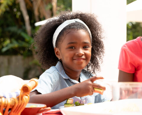 African American Girl Smiling And Looking At Camera During A Family Lunch In The Garden