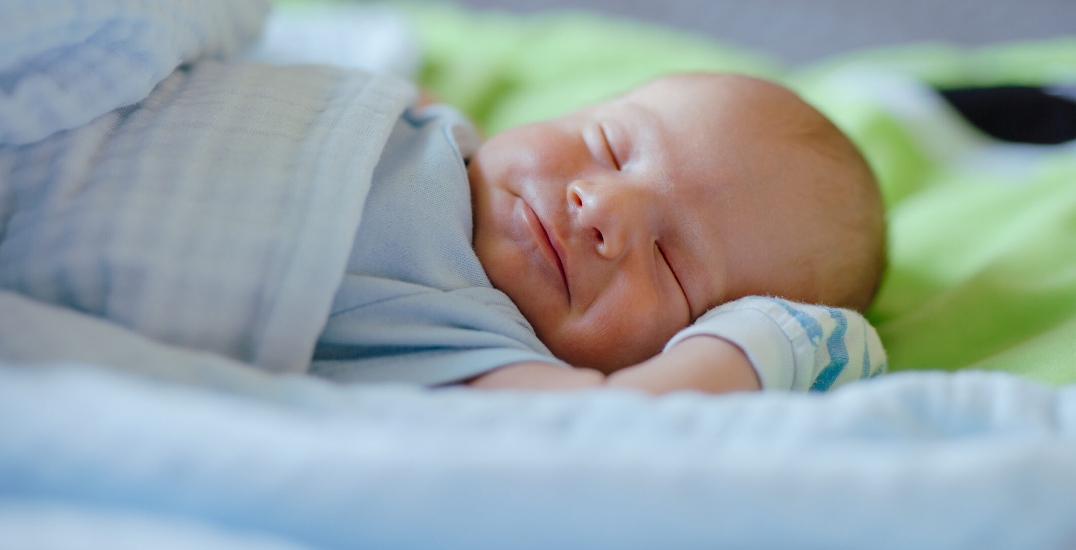 Smiling Newborn Baby Dreaming On The Bed
